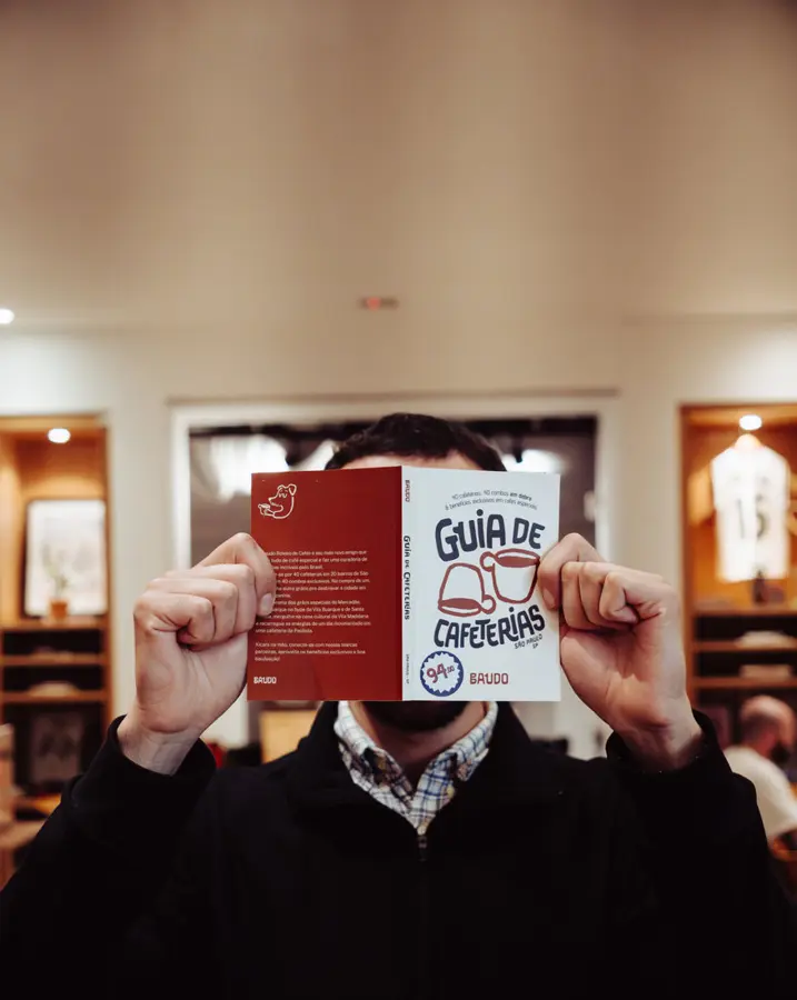 Pessoa segurando o Guia de Cafeterias